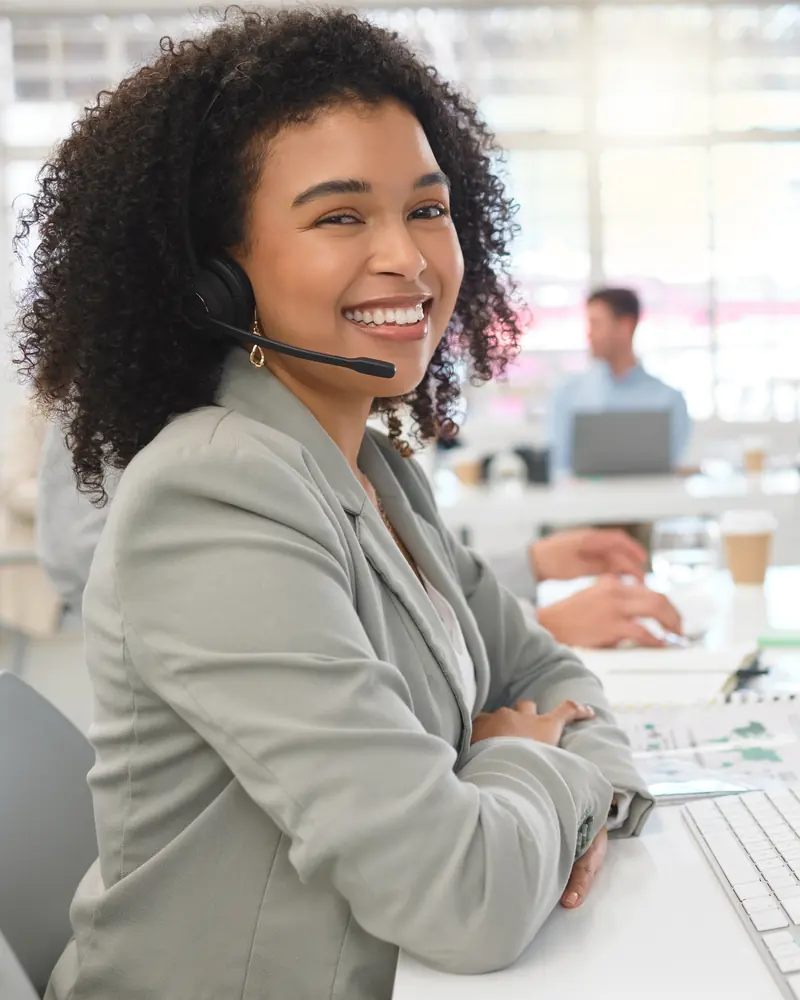 Asesora con auriculares sonriendo mientras atiende una llamada