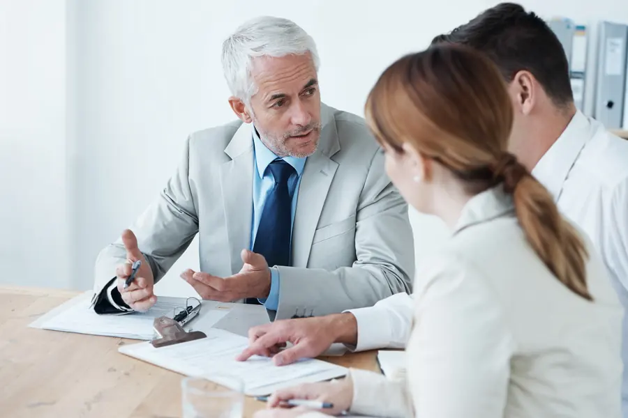 Asesor explicando un documento a dos clientes